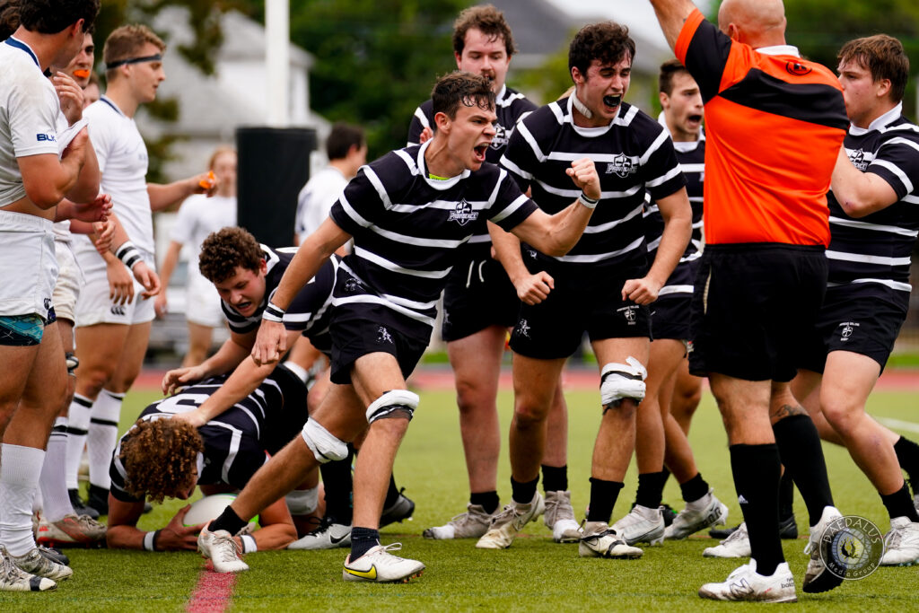 Rugby players in black and white striped shirts celebrating a play